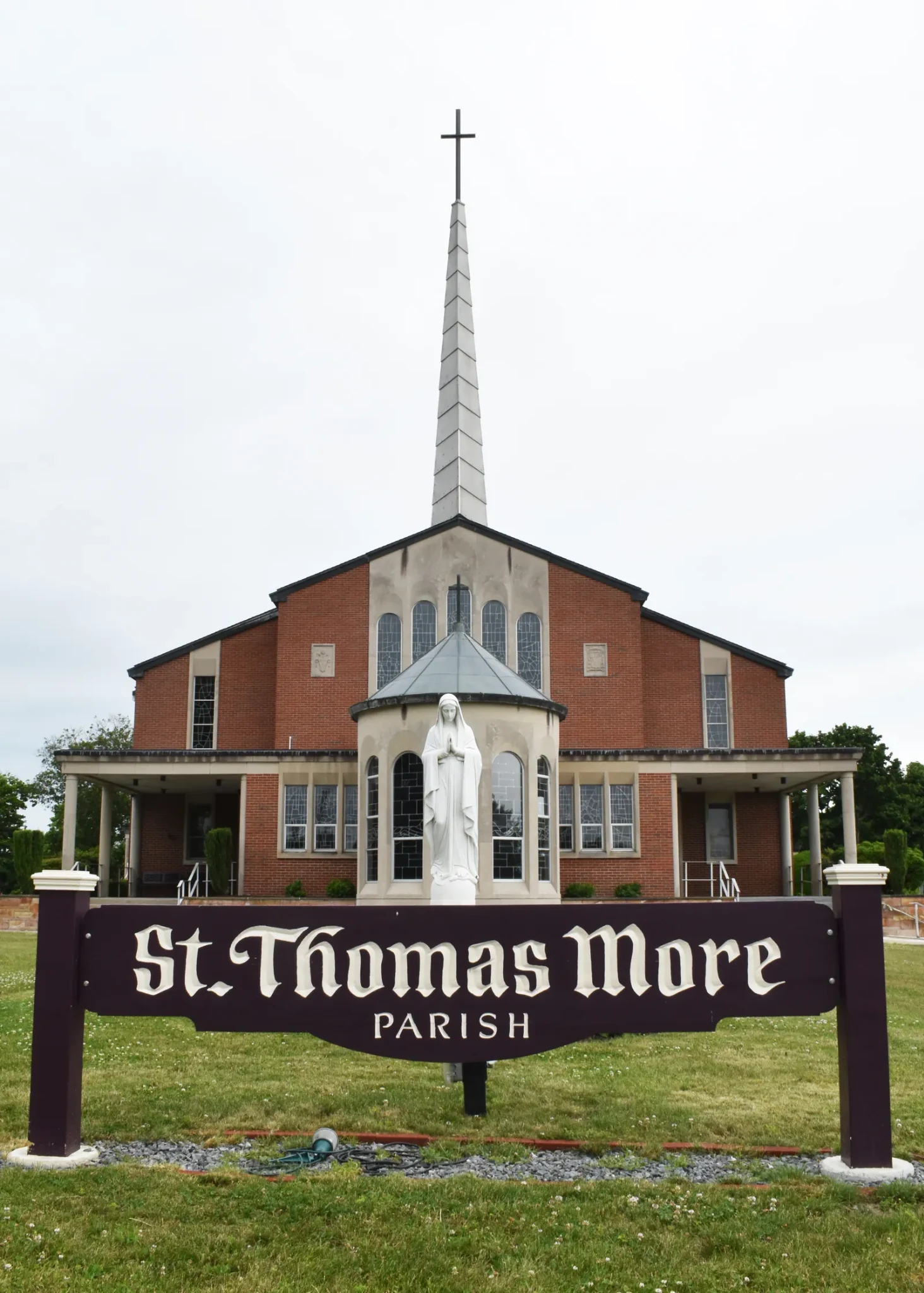St. Thomas More Parish church, with a statue of Mary and the parish sign in front.